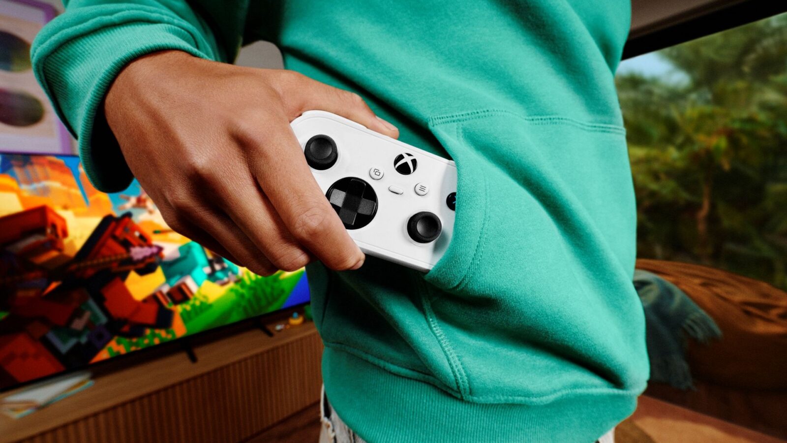 Official Xbox Nano Controller white compact controller shown in a person's hand near a hoodie pocket, courtesy of Xbox Wire